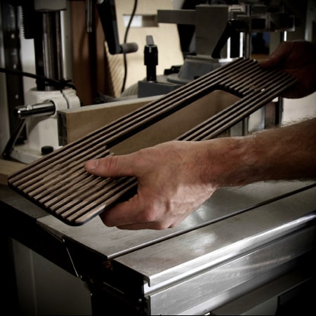 Hands holding Ruark Audio R5 MiE’s wood grille
